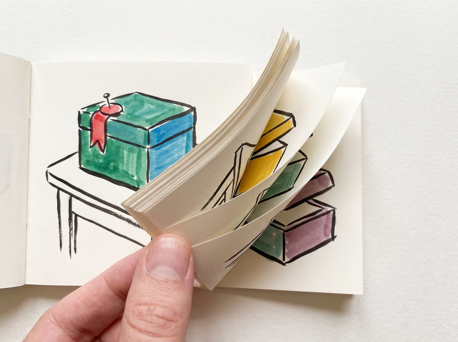 A thumb holds open a small flip book. The first page is a finished drawing of a closed box with a ribbon pinned to the corner. The pages behind it show the lid lifting a little more each time until the box is open.