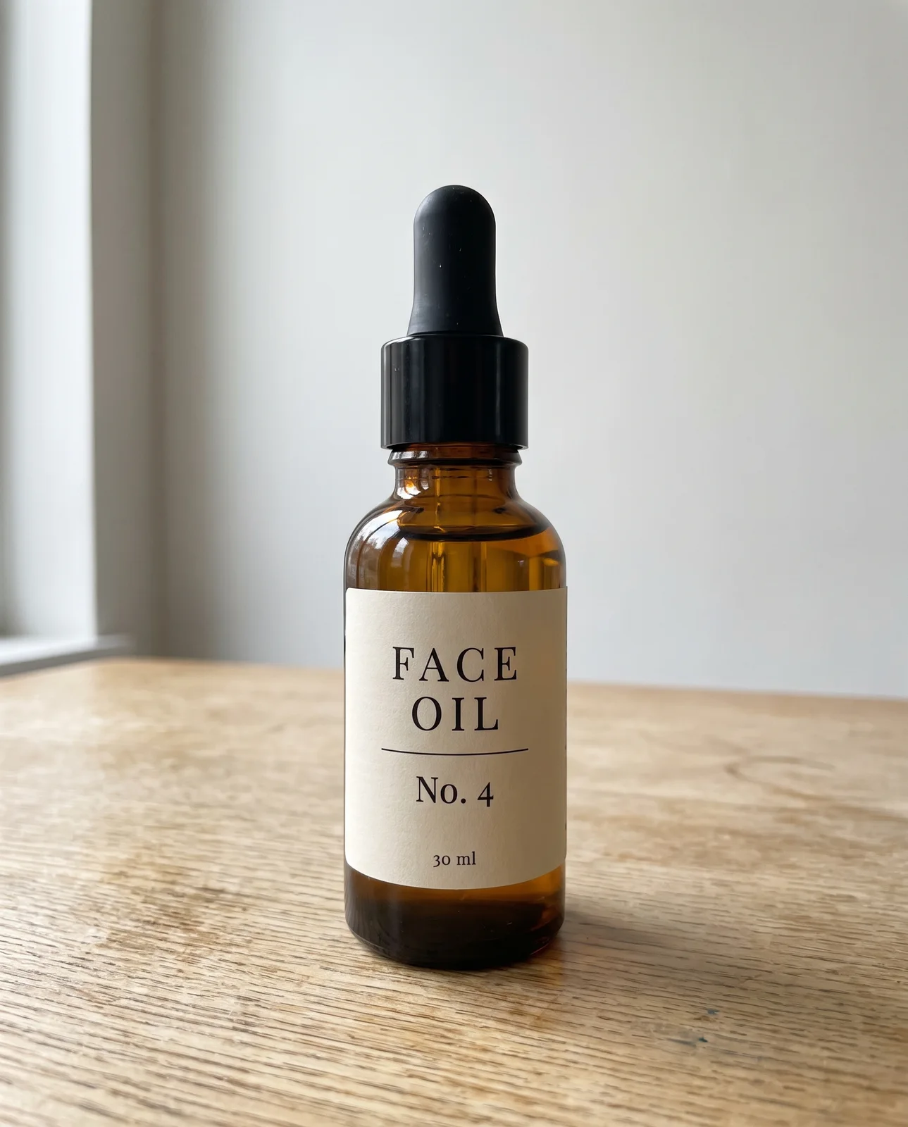 Phone photo of an invented amber glass face oil dropper bottle with a cream label reading FACE OIL No. 4, on an oak table.
